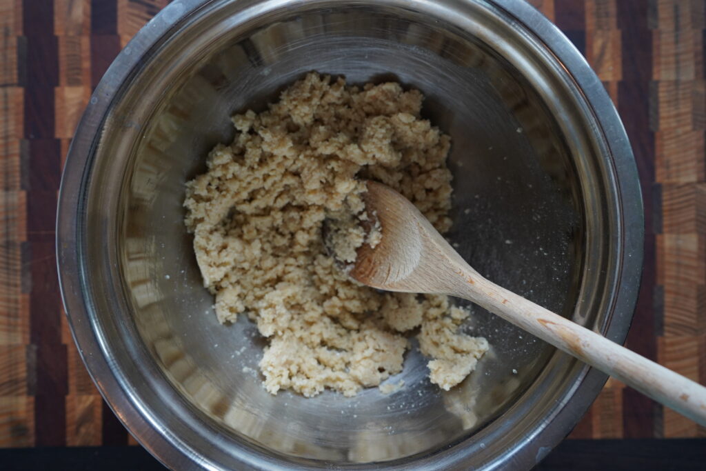 almond flour dough mixed by a wooden spoon in a silver bowl