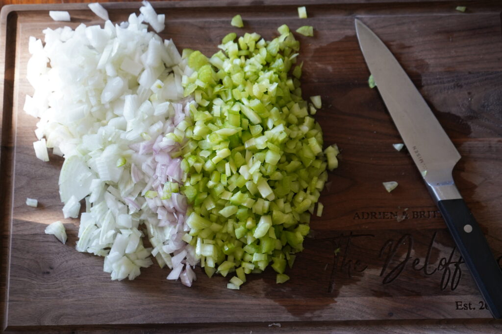 a cutting board with chopped onion, shallot and celery on it