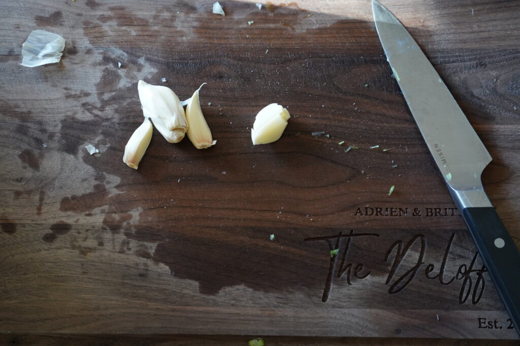 a cutting board with whole garlic cloves on it