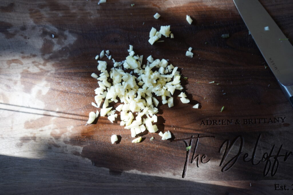 a cutting board with chopped garlic cloves