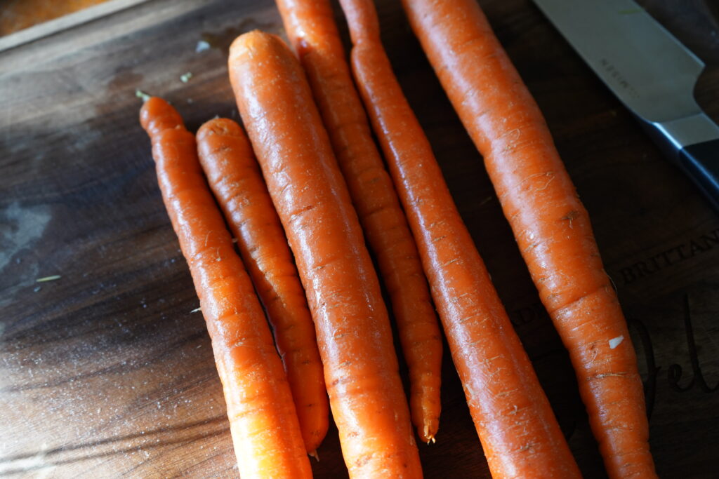 six whole, wash carrots on a cutting board