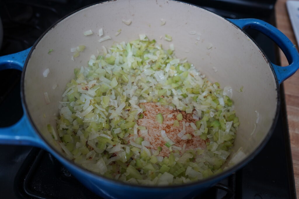 chopped vegetables being sauteed in a Dutch oven