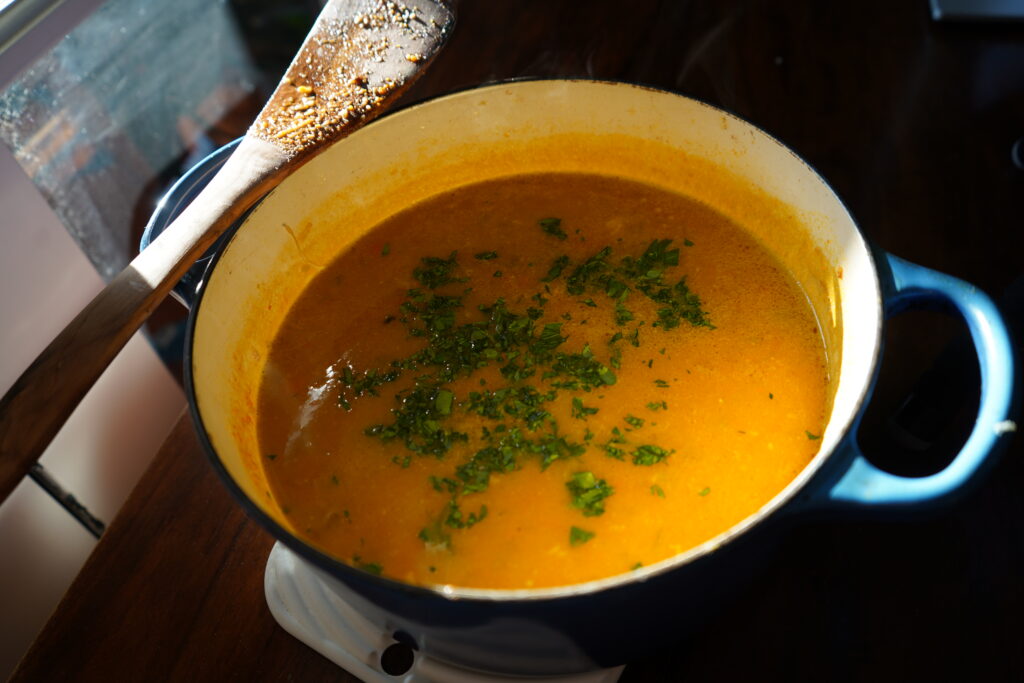 A Dutch oven full of a penicillin soup topped with cilantro