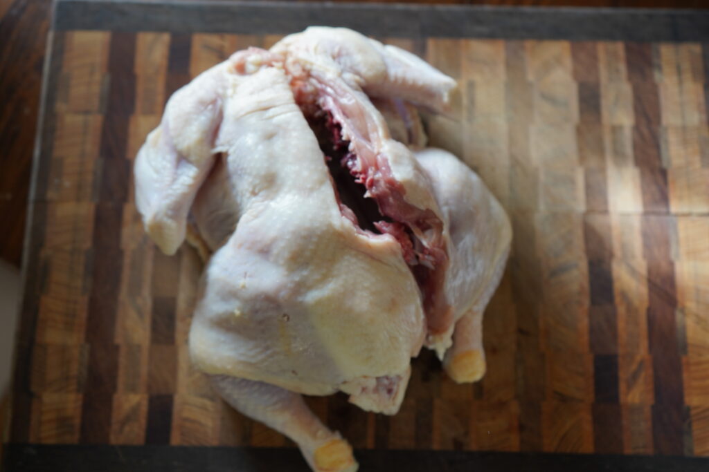 Whole chicken, cleaned and cut down the back, ready for baking or roasting.