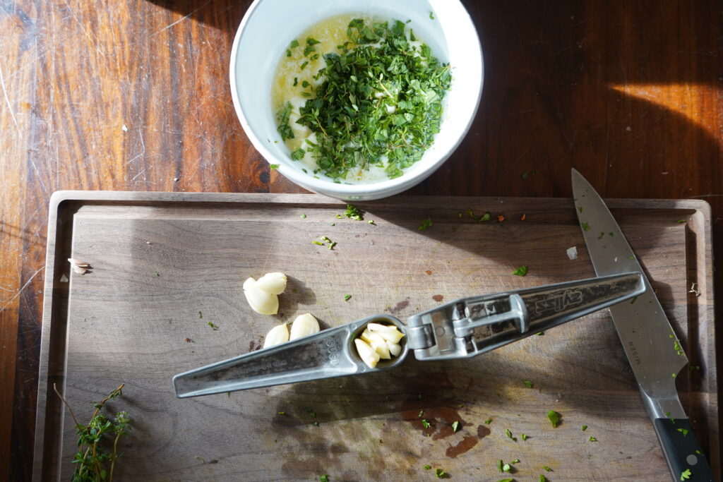 Garlic crusher full of garlic, ready to be crushed to make the garlic herb butter.