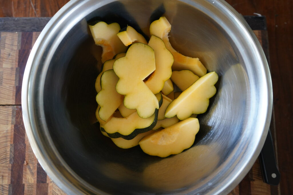 Cut up acorn squash in a mixing bowl.