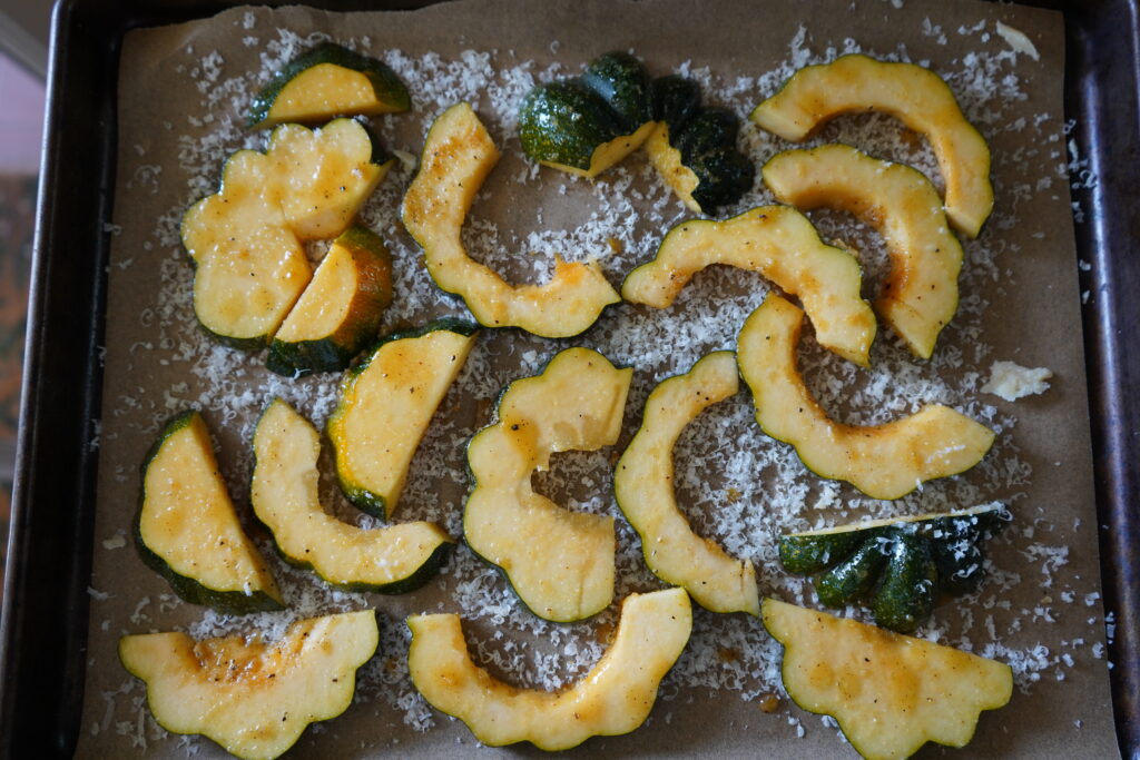 Acorn squash laying on a bed of shredded parmesan cheese.