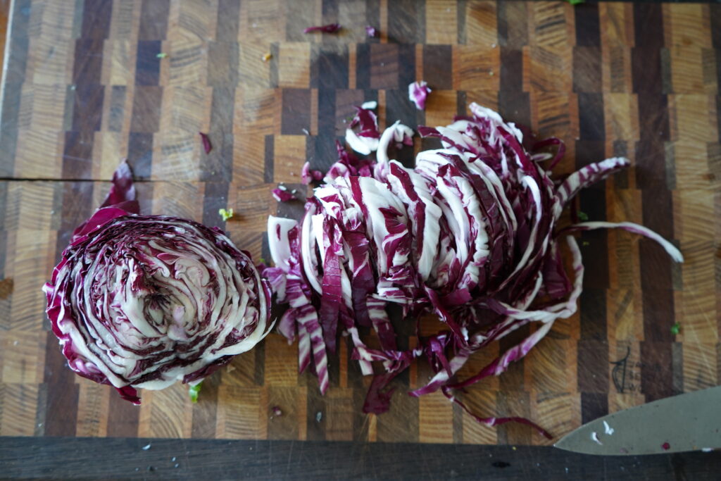 Radicchio cut in half on a cutting board and one half has been chopped in thin strips.