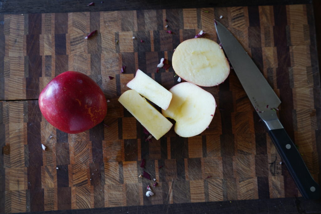 An apple being chopped on a cutting board.