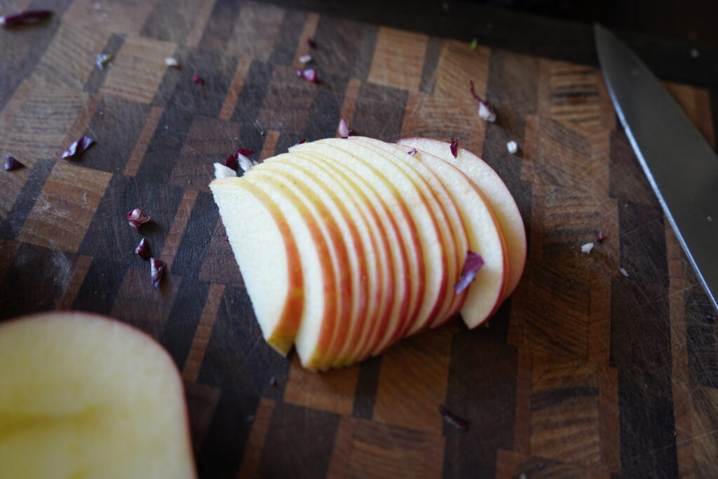 An apple on a cutting board sliced thin.