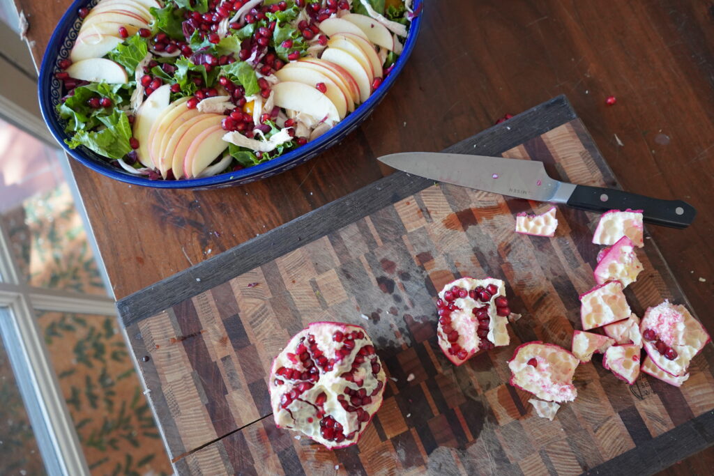 A cut up pomegranate on a cutting board.