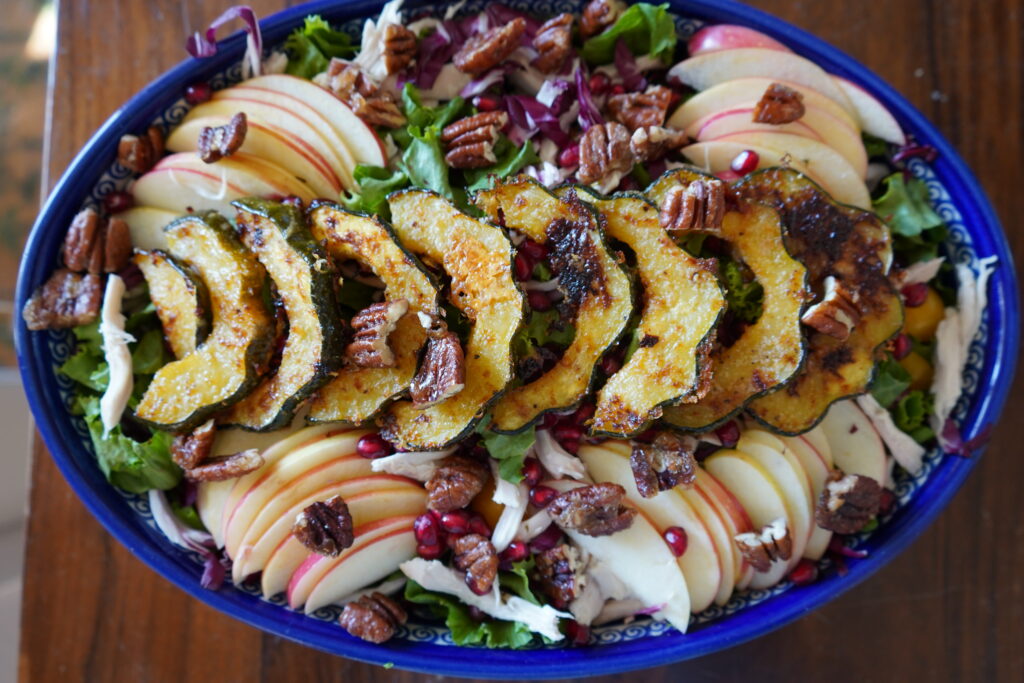 A big salad full of squash, pecans, apples and more.