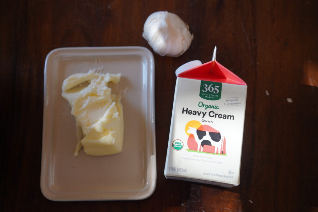 Soft butter, a head of garlic and a container of heavy cream