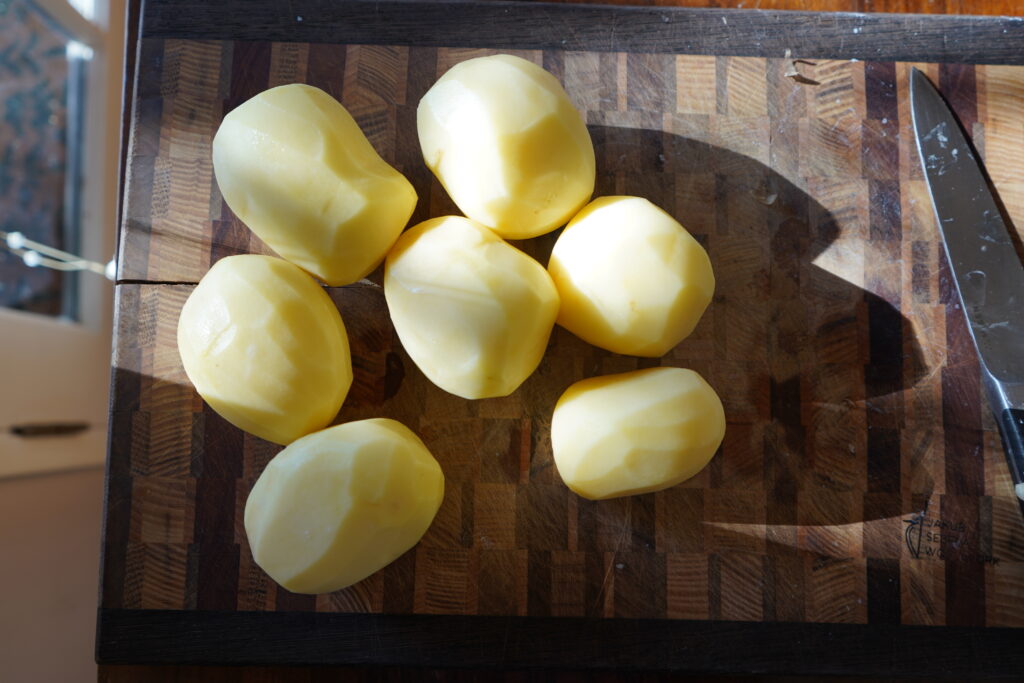 seven peeled golden potatoes on a cutting board