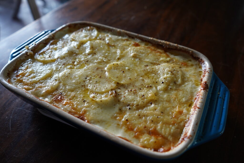 Potatoes au Gratin (Dauphinois) - French Scallop Potatoes in a blue baking dish on a table