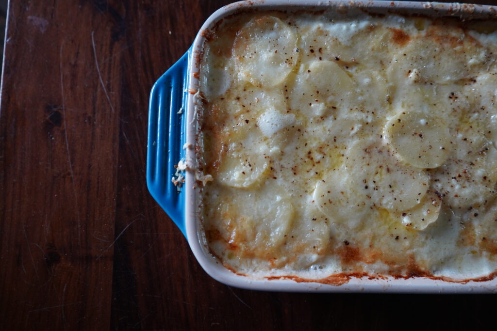 Scalloped Potatoes French style in a blue baking dish.