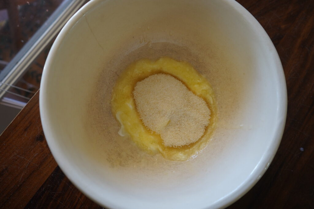 a mixing bowl with melted butter at the bottom with sugar poured on top