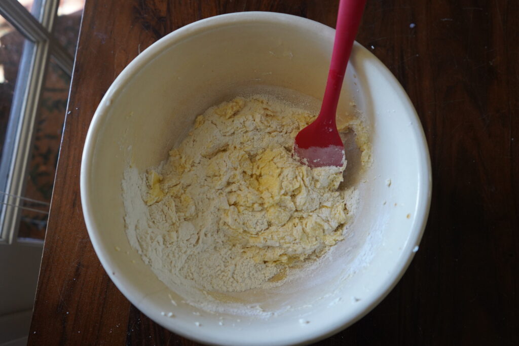 flour being add to the sugar mixture  in a mixing bowl