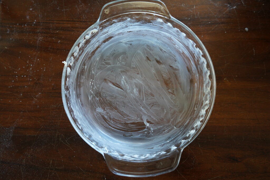 A pie dish that has been greased with butter