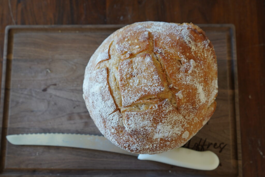 a loaf of bread on a cutting board next to a bread knife