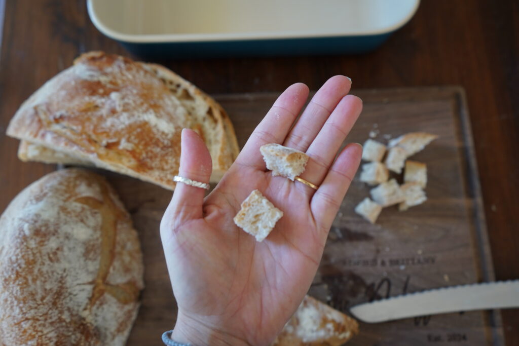 a hand holding sourdough that has been cut up into cubes