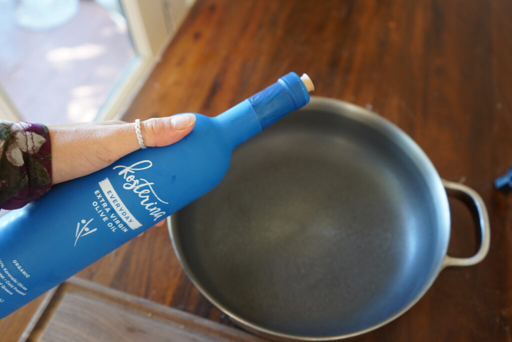 an olive oil bottle being poured onto a pan