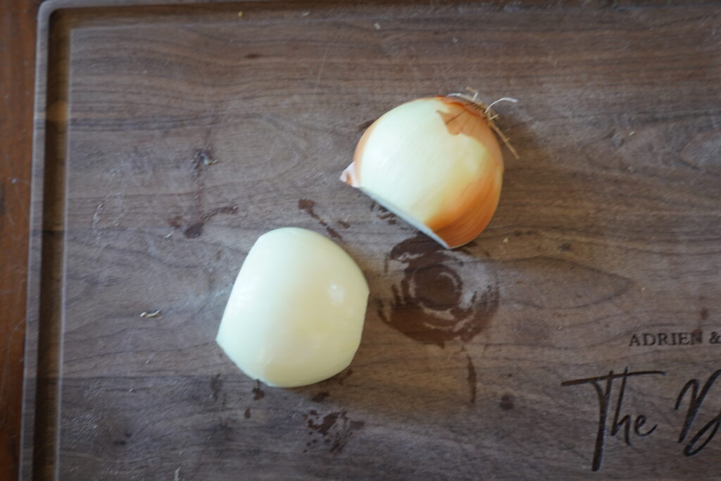 a yellow onion cut in half on a cutting board