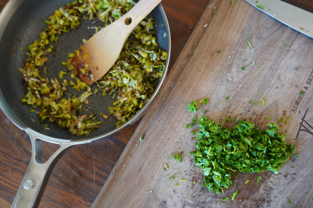 chopped cilantro on a cutting board next to a pan of sauteed vegetables