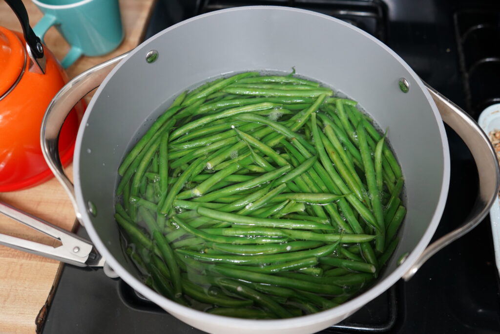 a pot of boiling water and green beans inside boiling