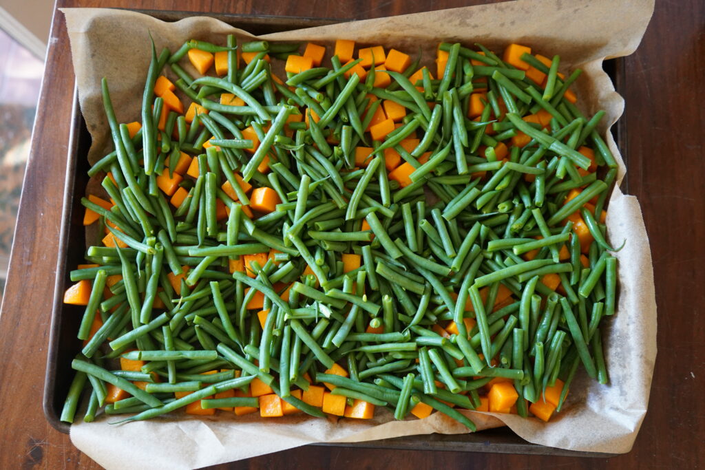 butternut squash and green beans on a baking tray