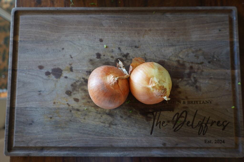 two yellow onions on a cutting board