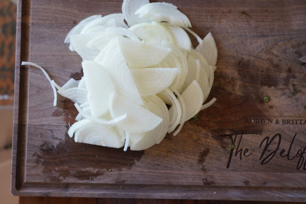 a pile of thinly sliced onions on a cutting board