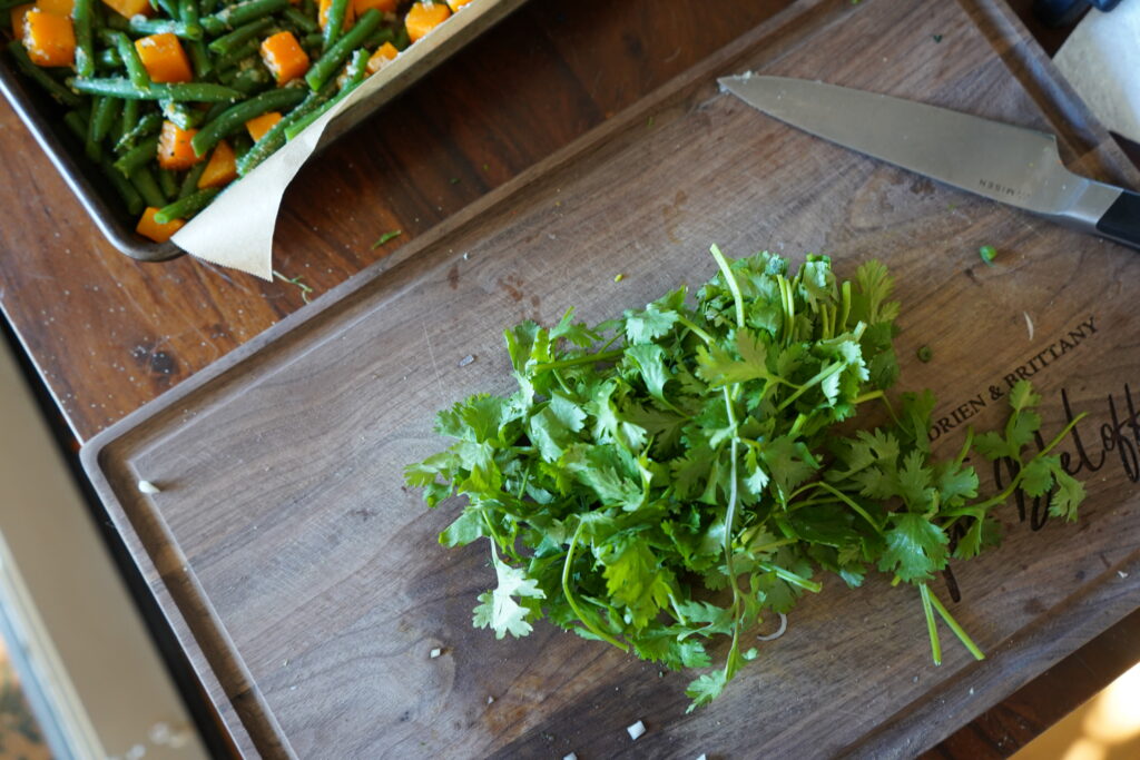 a cutting board with a bushel of cilantro ready to be chopped