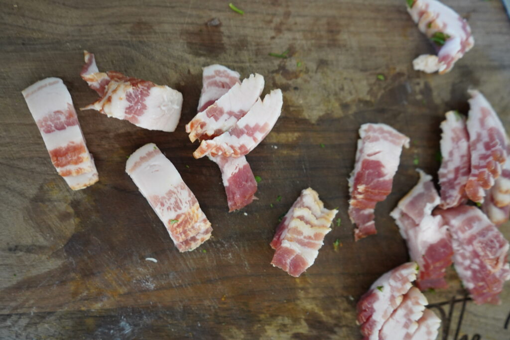 cut up uncooked bacon on a cutting board