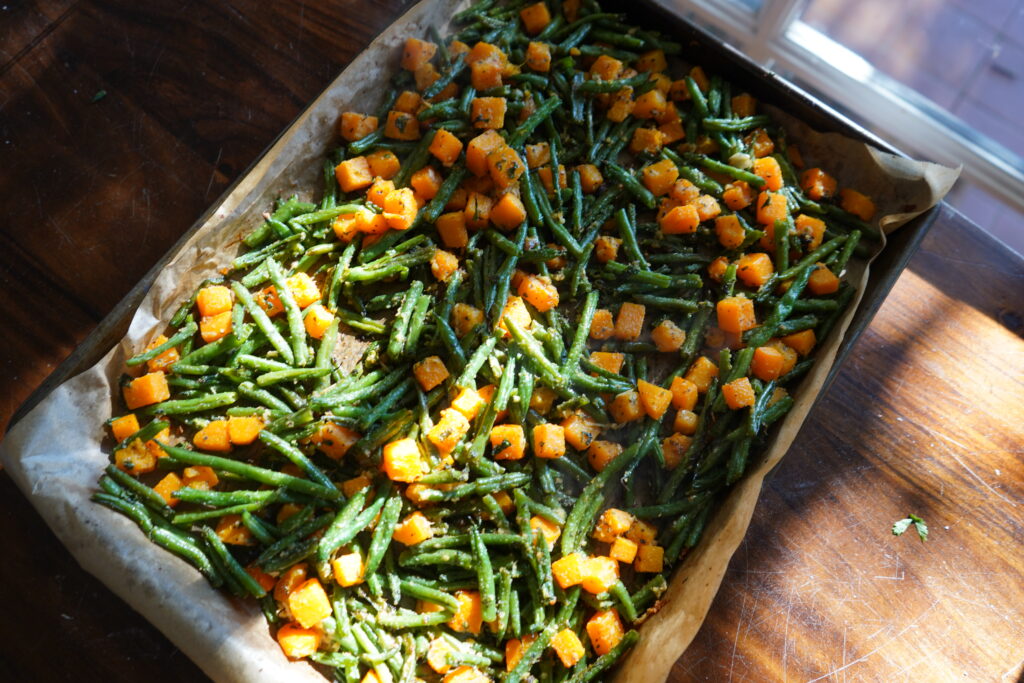 A sheet pan of butternut squash in cubes and beans that are green