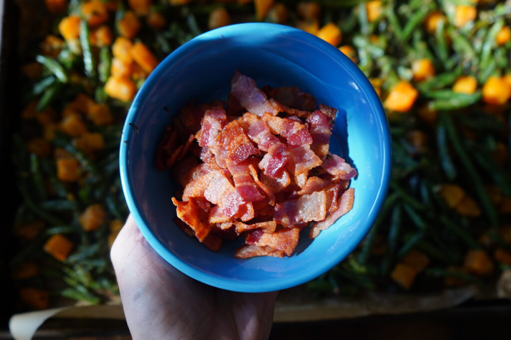 a small blue bowl with cooked bacon inside