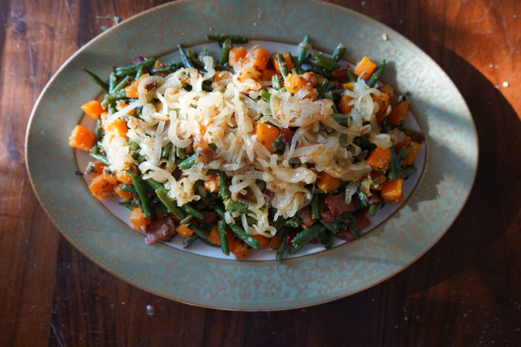 a beautiful serving plate with a pile of vegetables with caramelized onions ontop