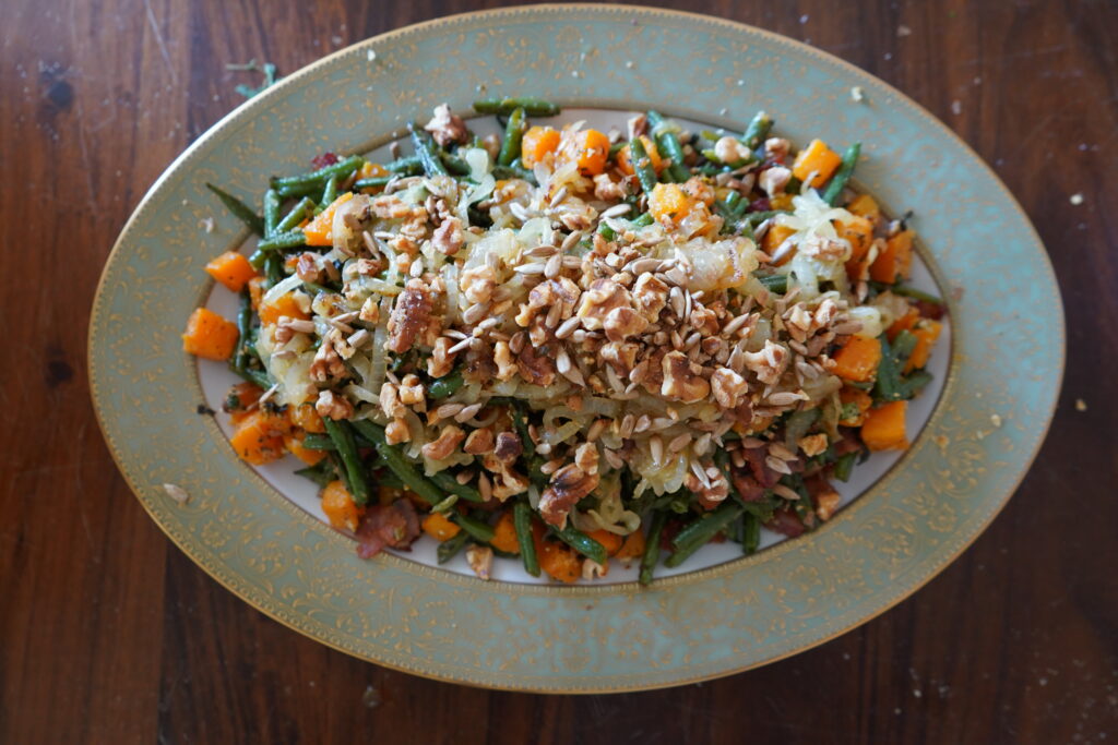 a serving plate with bakes beans and squash topped with baked walnuts