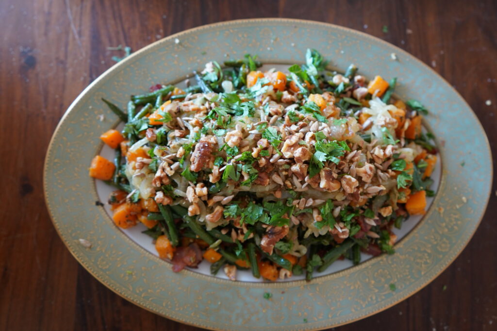 bake vegetables topped with onions, baked nuts and fresh cilantro