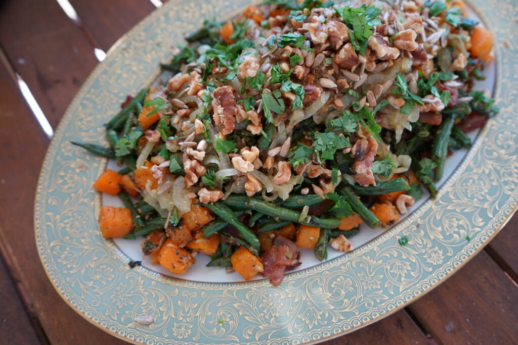 a plate of roasted vegetables top with baked nuts and herbs