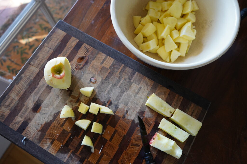 cut up apples in a bowl and a cutting board with cut up apples