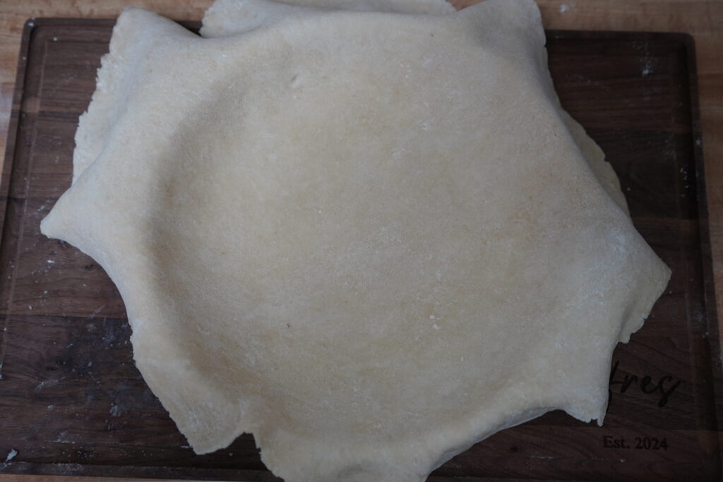 pie crust laying over a pie dish