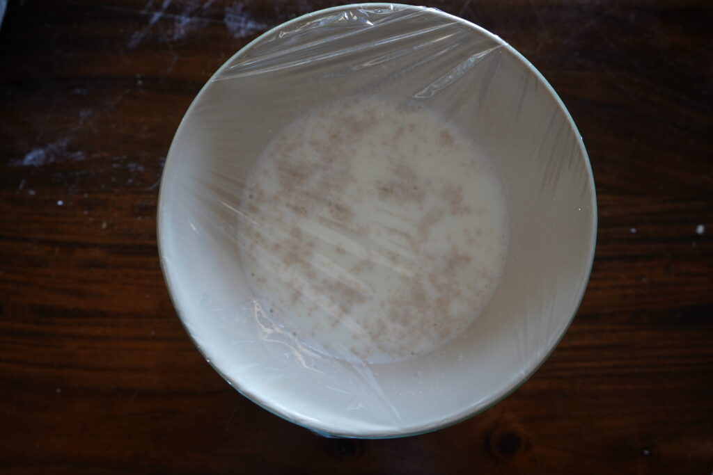 a yeast mixture in a bowl covered in plastic wrap