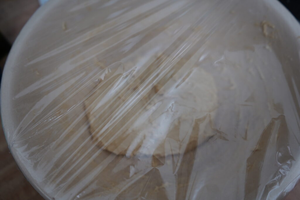 plastic wrap overing a bowl of dough