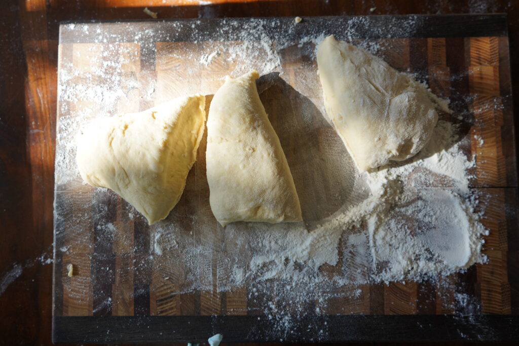 a slab of dough on a cutting board cut into thirds