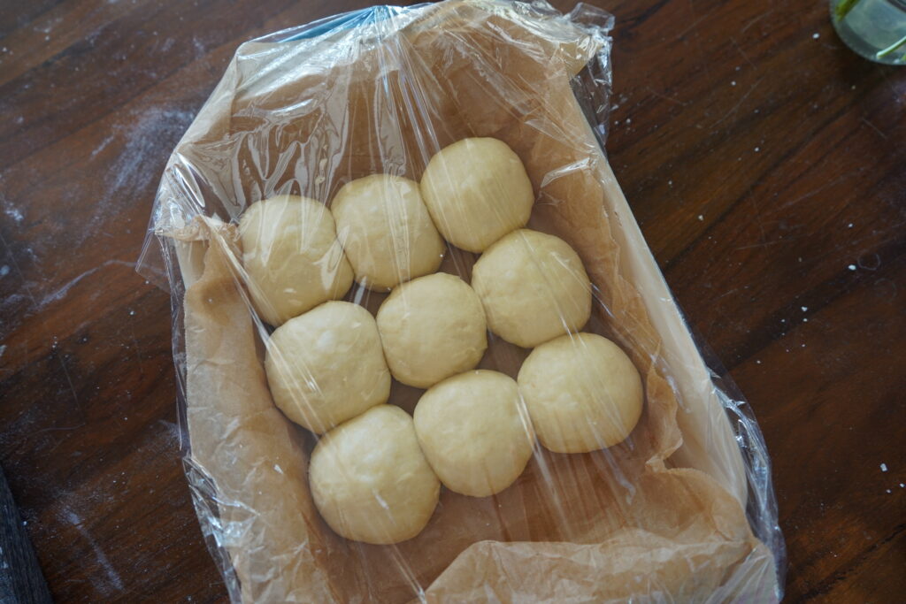 baking dish with bread rolls covered in plastic wrap