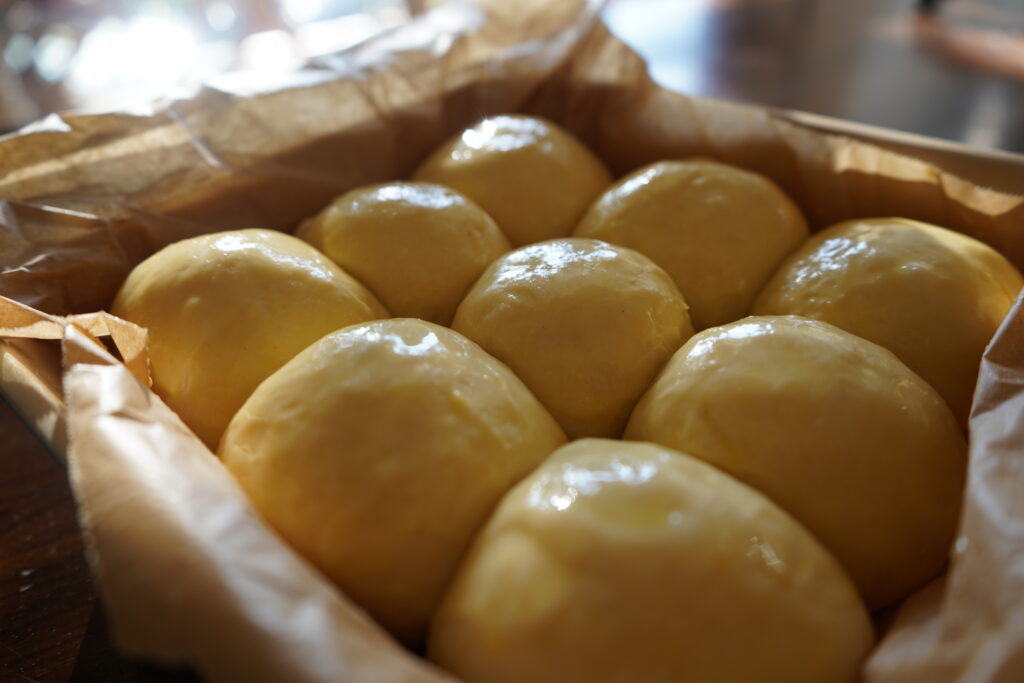 Dinner buns with egg wash on top ready to be baked