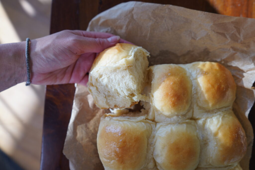 a hand pulling one of the bread rolls off of the whole batch