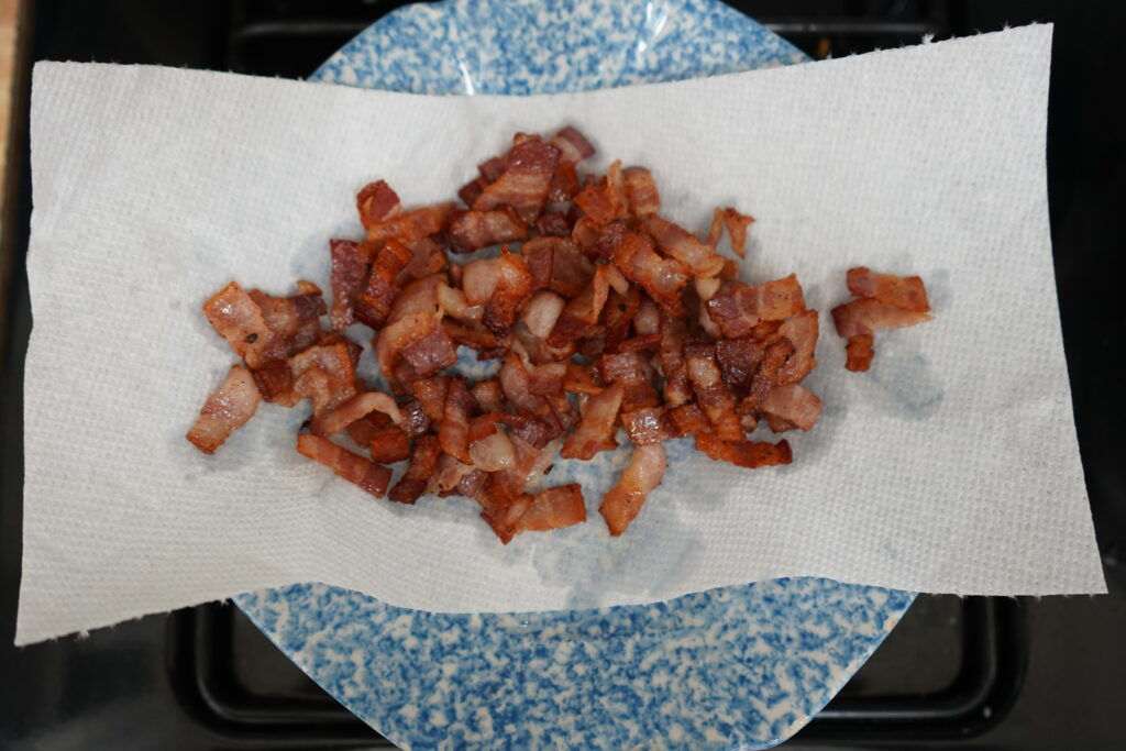 cooked bacon pieces on a paper toweled plate