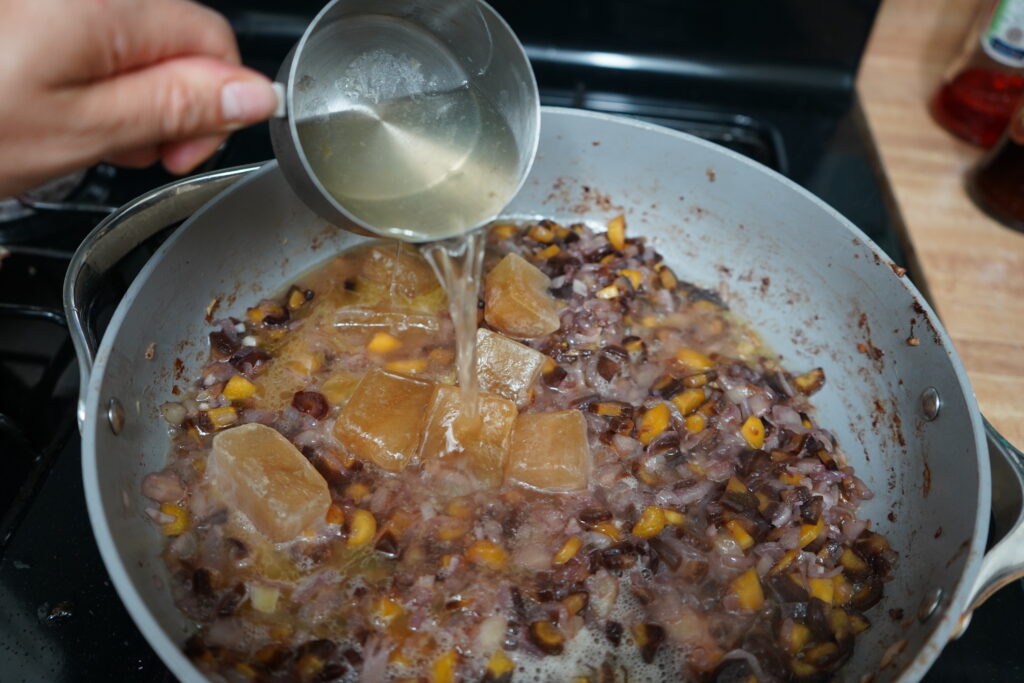 white wine being poured into a pan od vegetables